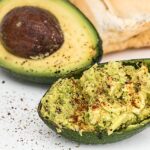 Avocado tagliato a fette su un piatto, pronto per essere utilizzato in ricette salutari per il colesterolo.