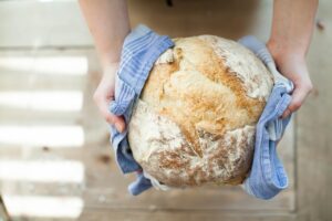 Pane fatto in casa con crosta dorata e interna compatta su un tavolo di legno.