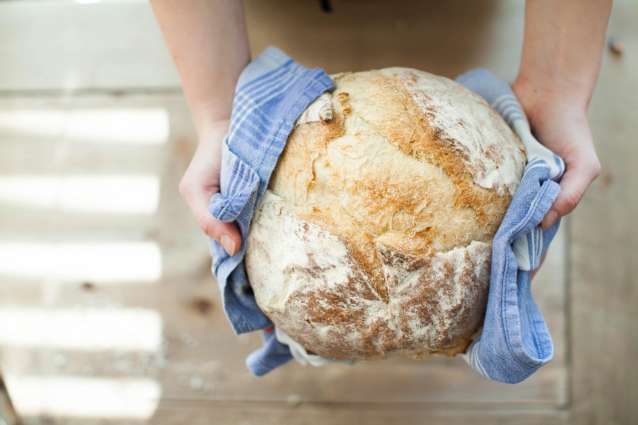 Pane fatto in casa con crosta dorata e interna compatta su un tavolo di legno.