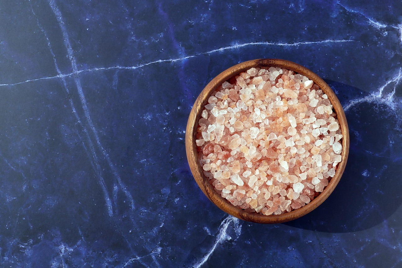 Sale rosa dell'Himalaya in un contenitore di vetro su sfondo bianco.