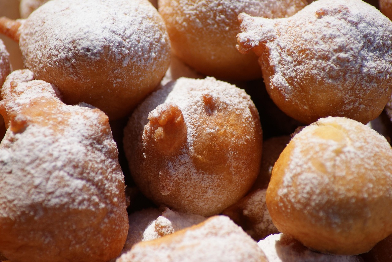 Frittelle veneziane dorate, spolverate di zucchero a velo, servite su un piatto elegante.