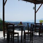 Trattoria rustica tra le colline, tavoli all'aperto con vista panoramica e piatti tradizionali.