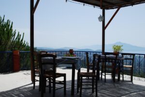 Trattoria rustica tra le colline, tavoli all'aperto con vista panoramica e piatti tradizionali.
