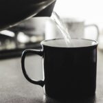 Un bicchiere di acqua tiepida su un tavolo al mattino, simbolo di benessere e idratazione.