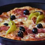 Pizza in teglia non lievitata, con bordi bassi e superficie compatta, evidenziando il problema di lievitazione.