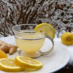 Tazza di acqua calda con fette di zenzero e limone, simbolo di una digestione migliorata.