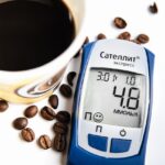 Tazza di caffè con chicchi di caffè e una mano che mescola, simbolo di salute e glicemia.